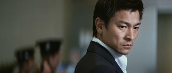 Movie still from “Infernal Affairs” (2002), directed by Alan Mak – A person wearing a suit and tie; Close Up shot, Low angle