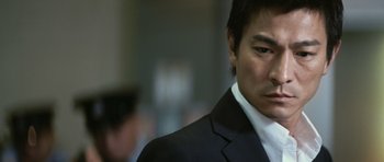 Movie still from “Infernal Affairs” (2002), directed by Alan Mak – A person wearing a suit and tie; Close Up shot, Low angle