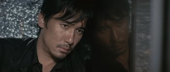 Movie still from “Infernal Affairs” (2002), directed by Alan Mak – A person wearing a black shirt; Close Up shot, High angle