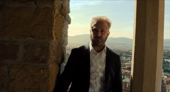 Movie still from “Inferno” (2016), directed by Ron Howard – A man in a suit standing next to a wall; Medium shot, Low angle