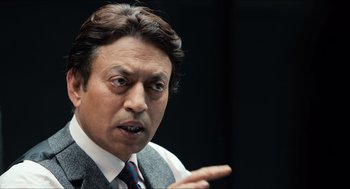 Movie still from “Inferno” (2016), directed by Ron Howard – A person wearing a suit and tie; Close Up shot, Over the shoulder angle