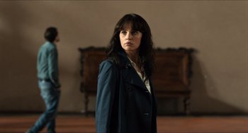 Movie still from “Inferno” (2016), directed by Ron Howard – A woman standing in front of a wall; Medium shot, Over the shoulder angle