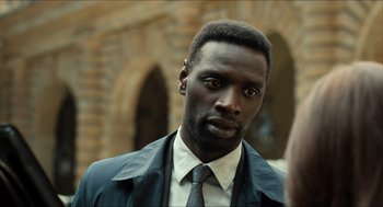 Movie still from “Inferno” (2016), directed by Ron Howard – A man in a suit and tie looking at the camera; Close Up shot, Over the shoulder angle