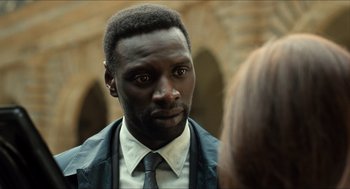 Movie still from “Inferno” (2016), directed by Ron Howard – A person wearing a suit and tie; Close Up shot, Over the shoulder angle