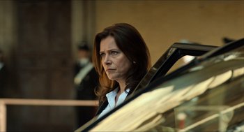 Movie still from “Inferno” (2016), directed by Ron Howard – A woman standing next to a parked car in a parking lot; Close Up shot, Low angle