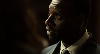 Movie still from “Inferno” (2016), directed by Ron Howard – A person wearing a suit and tie; Close Up shot, Over the shoulder angle