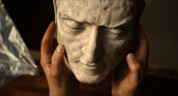 Movie still from “Inferno” (2016), directed by Ron Howard – A statue of a man's face with his hands on his head; Extreme Close Up shot, High angle