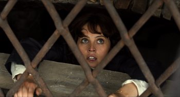 Movie still from “Inferno” (2016), directed by Ron Howard – A woman looking through the bars of an iron fence; Close Up shot, Overhead angle