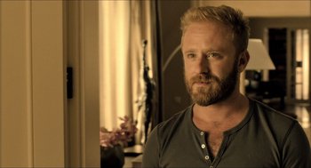 Movie still from “Inferno” (2016), directed by Ron Howard – A man with blonde hair and a beard looking at the camera; Close Up shot, Over the shoulder angle