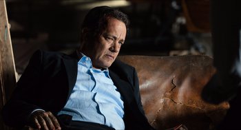 Movie still from “Inferno” (2016), directed by Ron Howard – A man in a suit sitting on a couch; Medium shot, High angle
