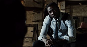 Movie still from “Inferno” (2016), directed by Ron Howard – A man sitting in a chair wearing a suit and tie; Medium shot, Low angle