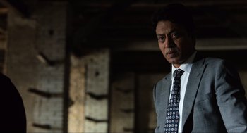 Movie still from “Inferno” (2016), directed by Ron Howard – A man in a suit and tie standing in front of a brick wall; Close Up shot, Low angle