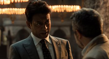 Movie still from “Inferno” (2016), directed by Ron Howard – A man wearing a suit and tie talking to another man; Close Up shot, Over the shoulder angle