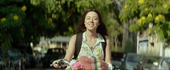 Movie still from “Ingrid Goes West” (2017), directed by Matt Spicer – A woman riding a bike down a street; Medium shot, Over the shoulder angle