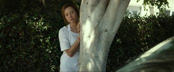 Movie still from “Ingrid Goes West” (2017), directed by Matt Spicer – A woman leaning against a tree in a park; Medium shot, High angle