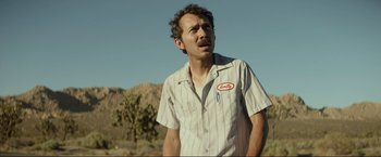 Movie still from “Ingrid Goes West” (2017), directed by Matt Spicer – A man in a white and red striped shirt is standing in the desert; Close Up shot, Low angle