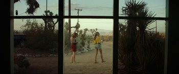 Movie still from “Ingrid Goes West” (2017), directed by Matt Spicer – Two women are standing in front of a window in the desert; Wide shot, Over the shoulder angle