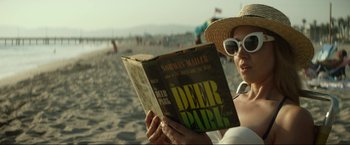 Movie still from “Ingrid Goes West” (2017), directed by Matt Spicer – A woman in a straw hat is reading a book on the beach; Medium shot, Low angle