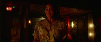 Movie still from “Ingrid Goes West” (2017), directed by Matt Spicer – A woman standing in the dark smiling for the camera; Medium shot, Over the shoulder angle