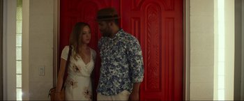 Movie still from “Ingrid Goes West” (2017), directed by Matt Spicer – A man and a woman standing next to each other in front of a red wall; Medium shot, Overhead angle