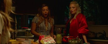 Movie still from “Ingrid Goes West” (2017), directed by Matt Spicer – Two women standing in front of a cake on top of a table; Medium shot, Low angle