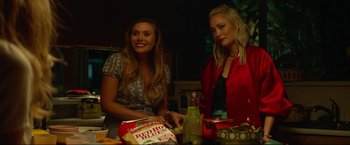 Movie still from “Ingrid Goes West” (2017), directed by Matt Spicer – Two young women sitting at a table with a bag of red peppers; Medium shot, Over the shoulder angle