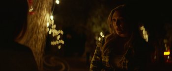 Movie still from “Ingrid Goes West” (2017), directed by Matt Spicer – A woman standing in the dark with lights in the background; Medium shot, Over the shoulder angle