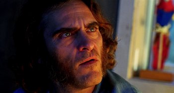 Movie still from “Inherent Vice” (2014), directed by Paul Thomas Anderson – A person with long curly hair; Close Up shot, Low angle