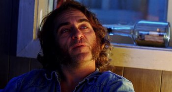 Movie still from “Inherent Vice” (2014), directed by Paul Thomas Anderson – A person with long curly hair; Close Up shot, Low angle