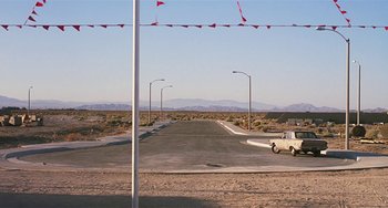 Movie still from “Inherent Vice” (2014), directed by Paul Thomas Anderson – An empty street with a car driving down it; Extreme Wide shot, High angle