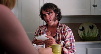 Movie still from “Inherent Vice” (2014), directed by Paul Thomas Anderson – A man sitting at a table with a cup of coffee; Close Up shot, Over the shoulder angle