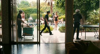 Movie still from “Inherent Vice” (2014), directed by Paul Thomas Anderson – A group of people walking around a building; Wide shot, Over the shoulder angle