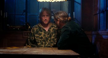 Movie still from “Inherent Vice” (2014), directed by Paul Thomas Anderson – A man and a woman sitting at a table talking to each other; Medium shot, Over the shoulder angle