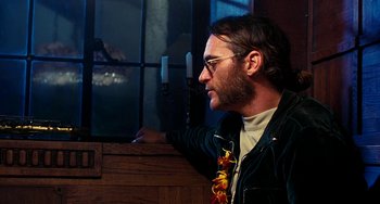Movie still from “Inherent Vice” (2014), directed by Paul Thomas Anderson – A man with glasses looking out of a window; Close Up shot, Over the shoulder angle