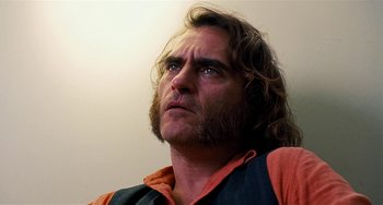 Movie still from “Inherent Vice” (2014), directed by Paul Thomas Anderson – A man with long hair looking up at the sky; Close Up shot, Low angle