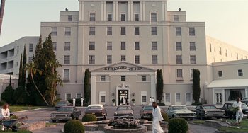 Movie still from “Inherent Vice” (2014), directed by Paul Thomas Anderson – A man walking in front of a large white building; Wide shot, Low angle