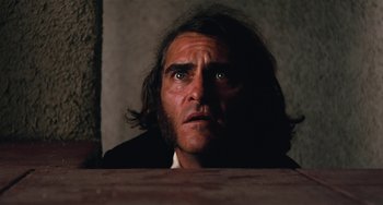 Movie still from “Inherent Vice” (2014), directed by Paul Thomas Anderson – A person with long hair looking at the camera; Close Up shot, Low angle