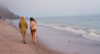 Movie still from “Inherent Vice” (2014), directed by Paul Thomas Anderson – A man and a woman walking on the beach; Wide shot, Over the shoulder angle
