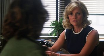 Movie still from “Inherent Vice” (2014), directed by Paul Thomas Anderson – A person sitting at a table holding a cell phone; Medium shot, Over the shoulder angle