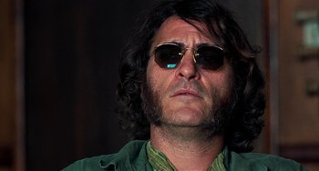 Movie still from “Inherent Vice” (2014), directed by Paul Thomas Anderson – A person wearing sunglasses; Close Up shot, Low angle