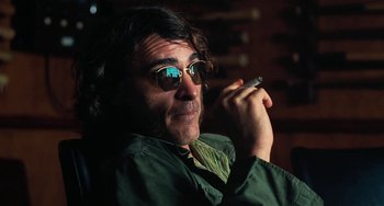 Movie still from “Inherent Vice” (2014), directed by Paul Thomas Anderson – A man with sunglasses is holding a cell phone; Close Up shot, Low angle