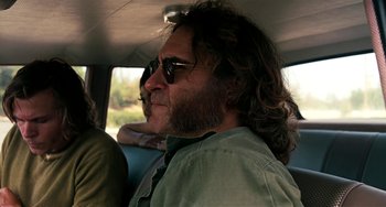 Movie still from “Inherent Vice” (2014), directed by Paul Thomas Anderson – A person in a car wearing sunglasses; Close Up shot, Over the shoulder angle