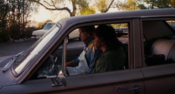Movie still from “Inherent Vice” (2014), directed by Paul Thomas Anderson – Two people sitting in the drivers seat of a car; Wide shot, Low angle