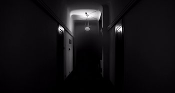 Movie still from “Inland Empire” (2006), directed by David Lynch – A hallway with a light hanging from the ceiling; Wide shot, Low angle