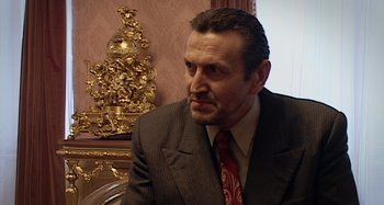 Movie still from “Inland Empire” (2006), directed by David Lynch – A person wearing a suit and tie; Close Up shot, Low angle