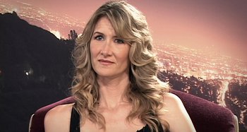 Movie still from “Inland Empire” (2006), directed by David Lynch – A woman with long blonde curly hair sitting in front of a city; Close Up shot, Over the shoulder angle