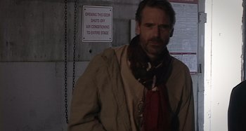 A man in a tan jacket and a red neck scarf