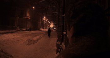 Movie still from “Inland Empire” (2006), directed by David Lynch – A person walking down a snowy sidewalk at night; Wide shot, High angle