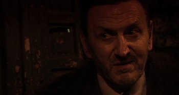 Movie still from “Inland Empire” (2006), directed by David Lynch – A person wearing a suit and tie; Close Up shot, Over the shoulder angle