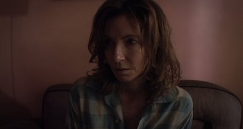 Movie still from “Inland Empire” (2006), directed by David Lynch – A person sitting on a couch; Close Up shot, Low angle